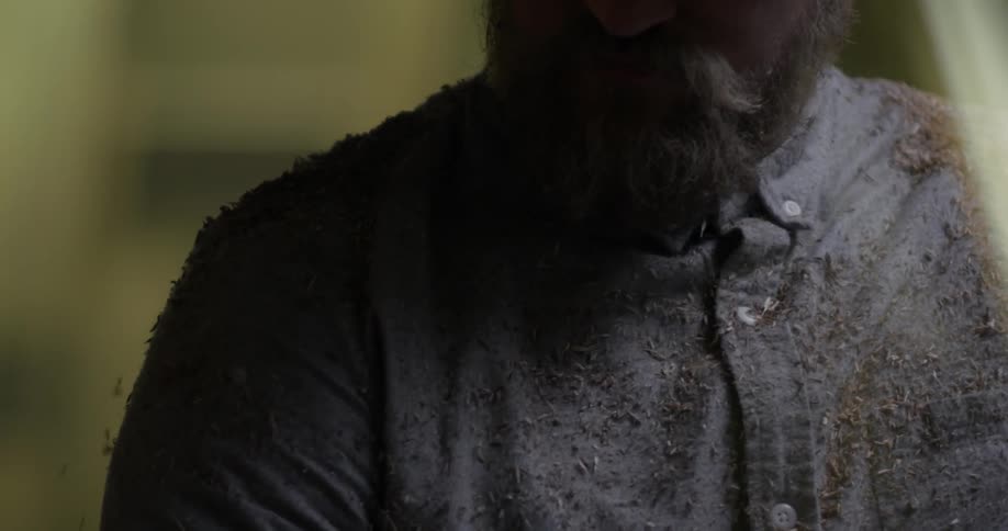 Bearded man brushes debris off of his shirt