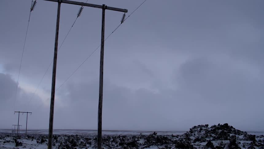 Power lines standing in a snowy wilderness on a cloudy day
