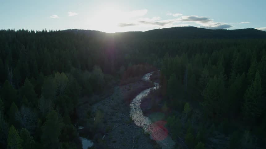 Sun rising over the hills with a small river winding through the trees