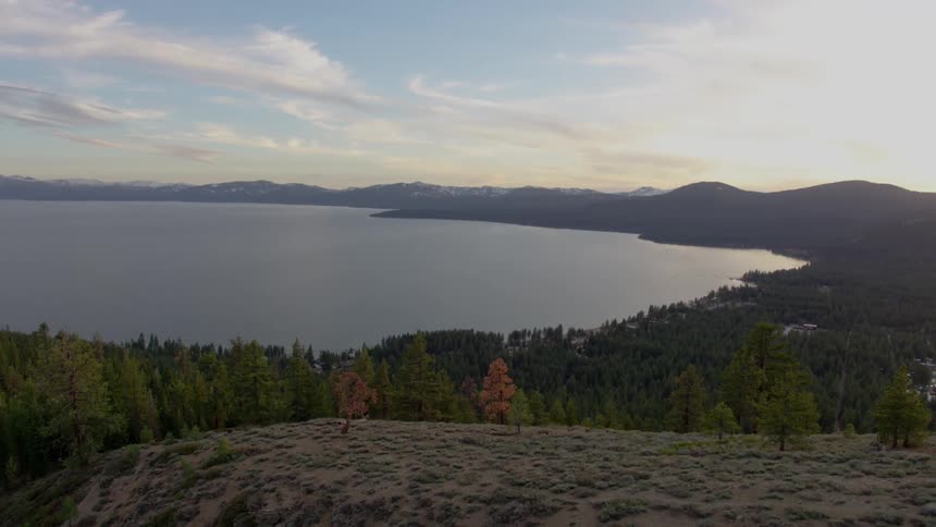 Slow moving drone shot of lake in the mountains with trees