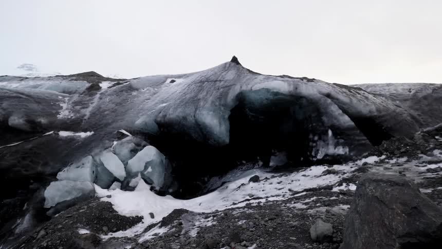 Snow sits in front of a cave entrance