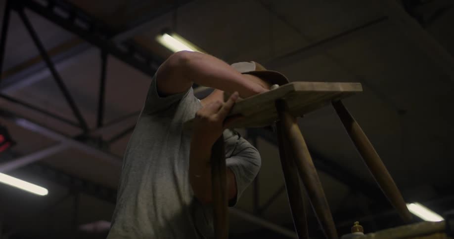 A wood worker works on a piece of furniture in a workshop