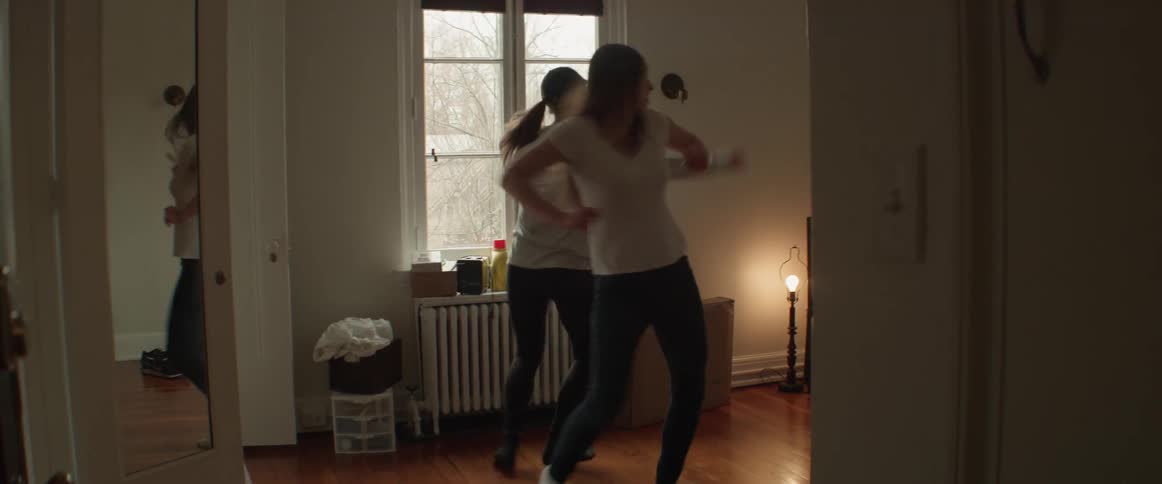 Two women dance in a living room
