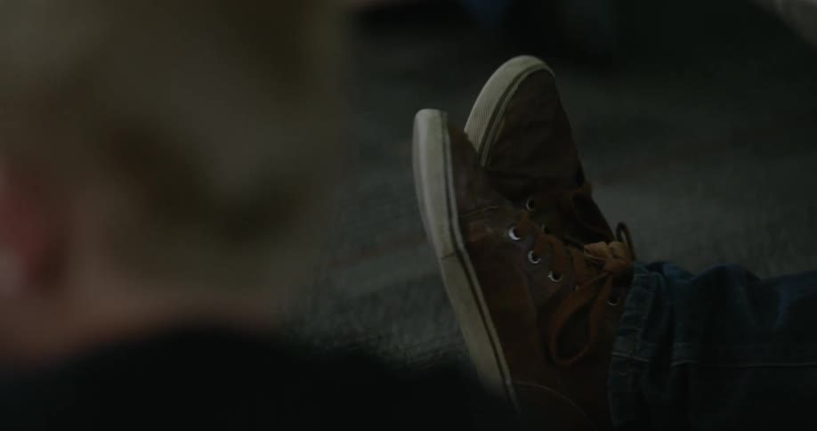 A person wearing tennis shoes taps their foot in the air