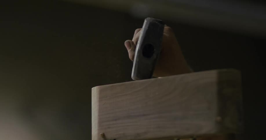 Person pounds on a piece of wood with a hammer