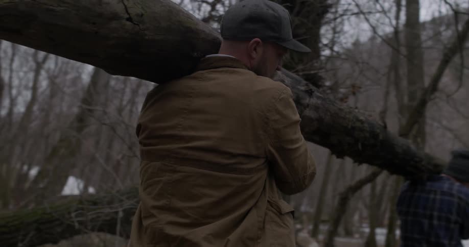 Two men carry a large log on their shoulders