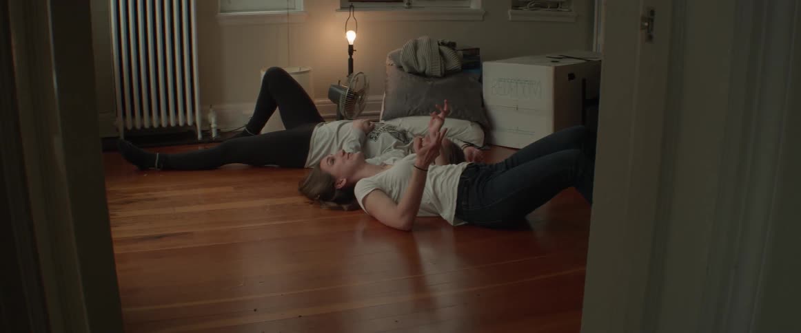 Two women lay and talk on the floor together