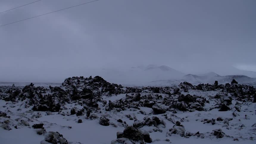Snow covers a field on a cloudy day