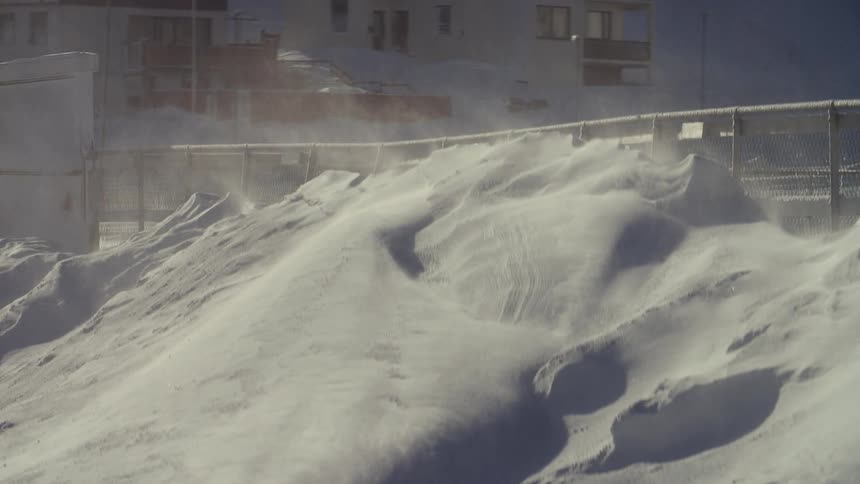 The snow is stacked high to the top of the fence