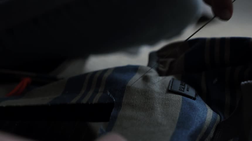 A woman stitches a piece of fabric