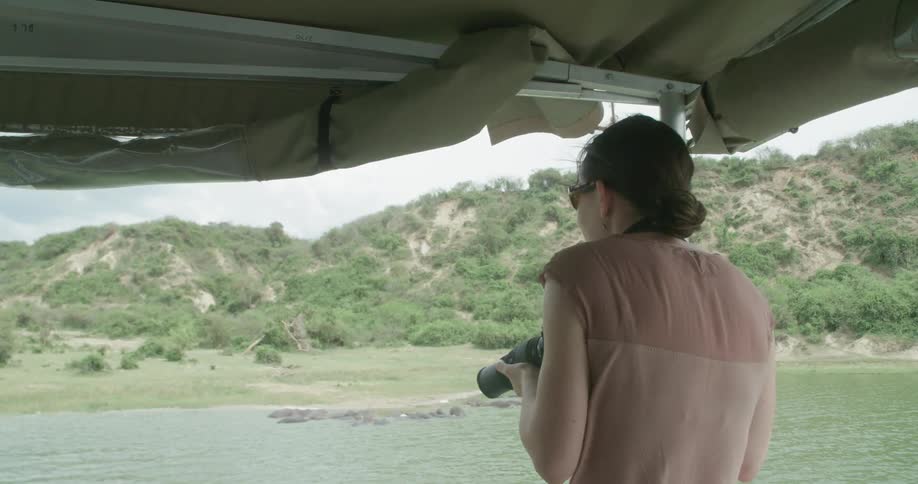 A woman on a boat takes a photograph of something on land
