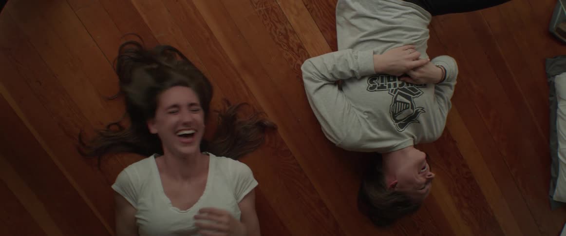 Two women lay on the floor laughing and talking