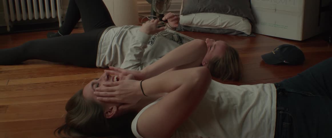 Two girls laugh on their new apartment floor