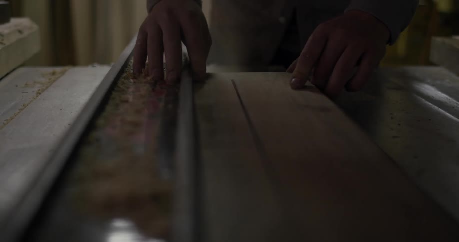 A wood worker cuts a piece of lumber