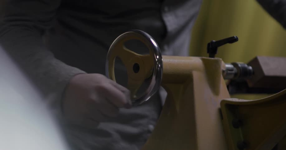 A man rotates a metal wheel with his hand