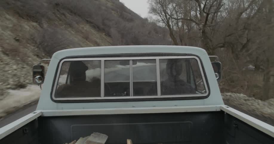 Two men ride in a truck on a mountain road