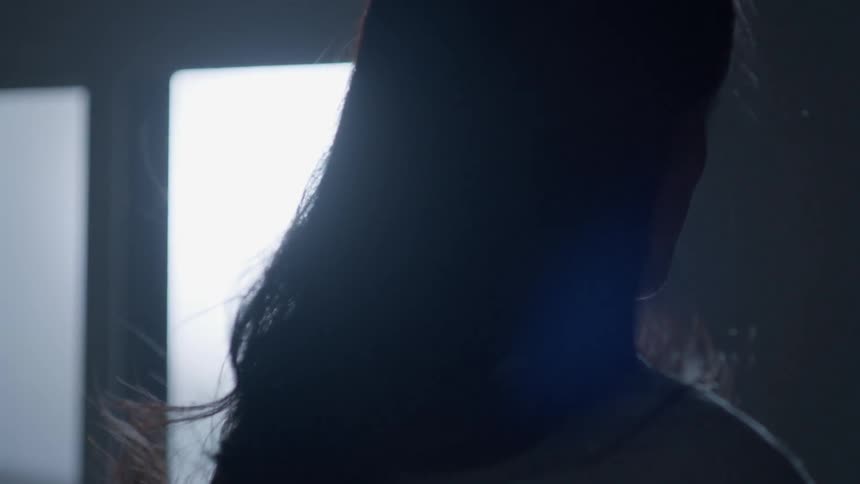 A woman stands in a dark room