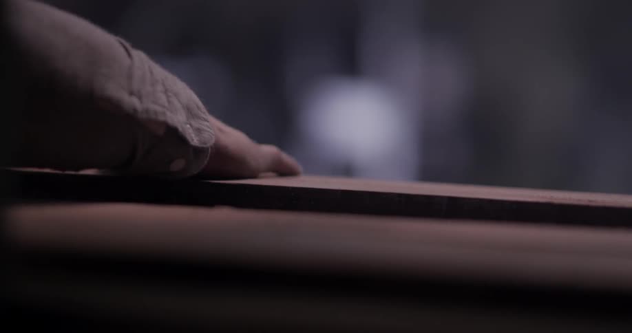 A man brushes the sawdust off a board