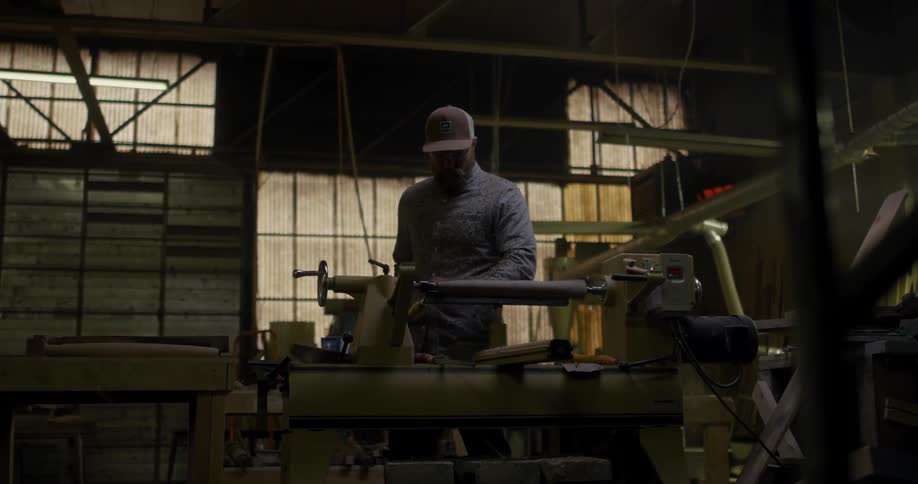 A man is working in his shop carving a bat on a machine