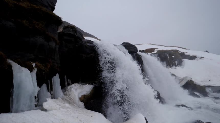 The waterfall pours over into the ice below