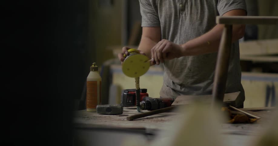 A man sands a small piece of wood