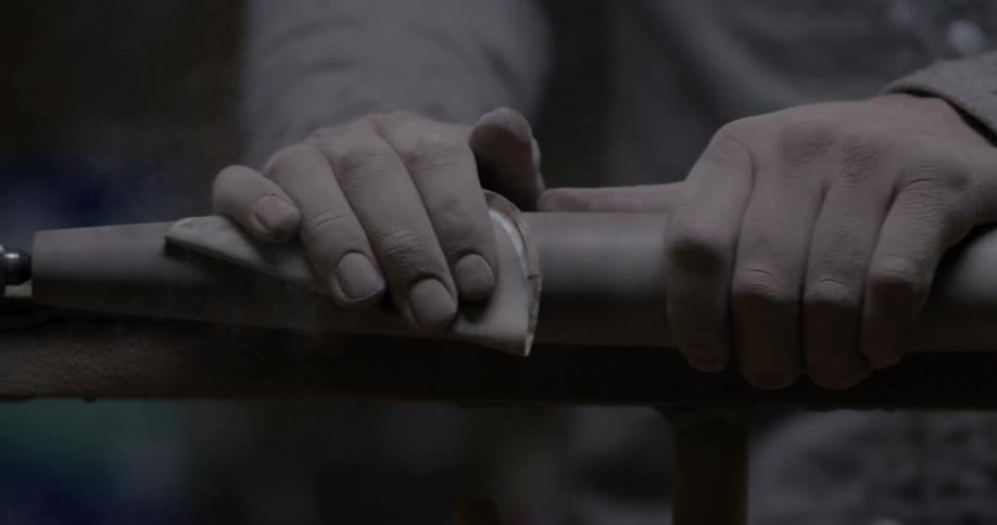 A man sands wood being turned in a lathe