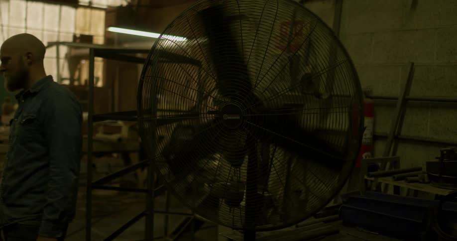A man turns on a fan in a warehouse