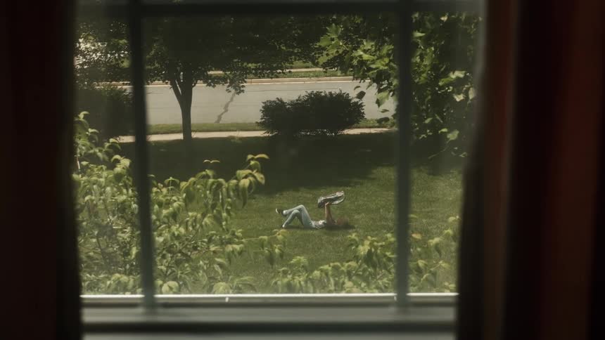 Woman crosses her legs as she lays on her back on the grass