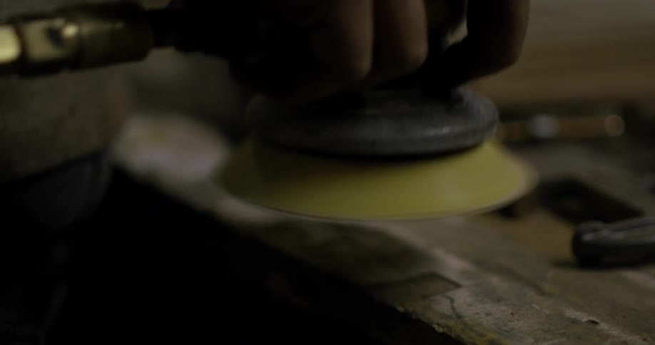 Person holds a small buffer to a piece of metal