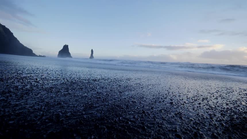 Rocky beach at sunrise with water splashing to shore