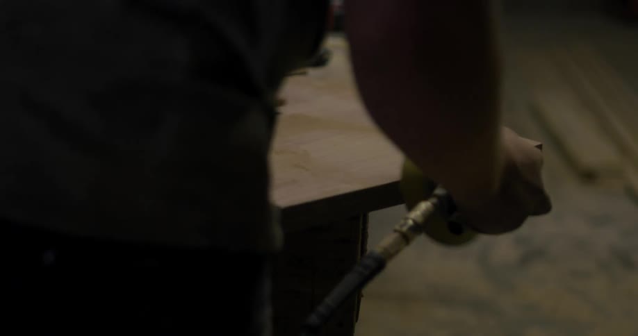Person sanding a piece of wood indoor