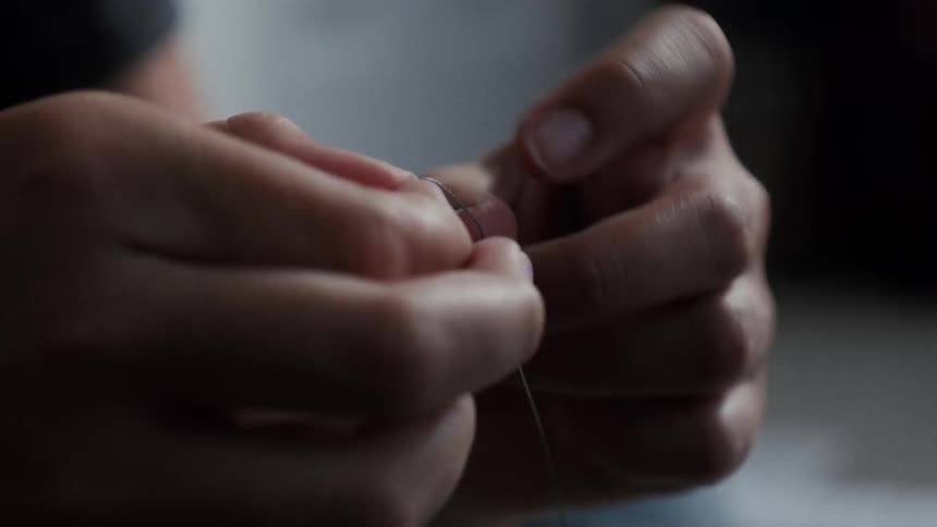 A woman threads a needle