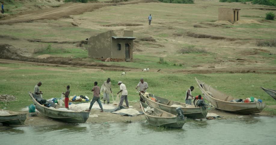 People with boats stand at the water's edge