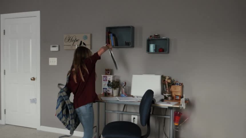 A girl enters a room and goes over to a desk