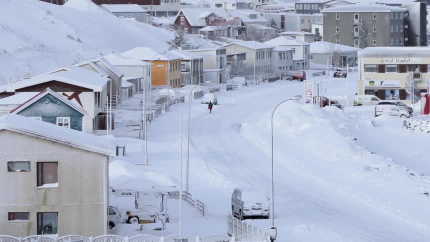 A van travels down a snow covered town road