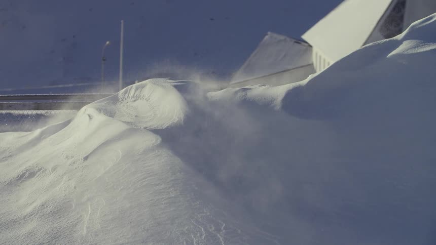 Snow drifts off of a hill in the wind