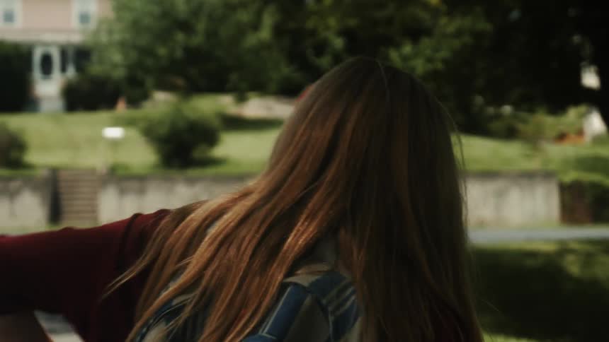 A girl walks on a sidewalk with a backpack