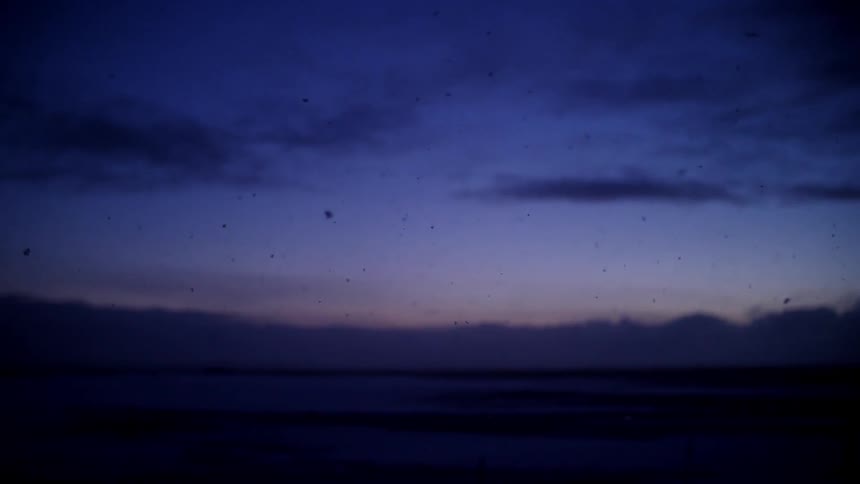 Soot floats to the ground outside at dusk