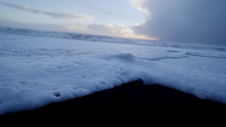 Ocean waves foam as they come to shore on the sand