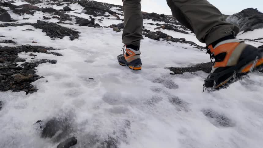 A hiker walks in the snow and ice up a hill