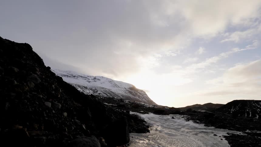 Snowy mountains sit under a cloudy sky