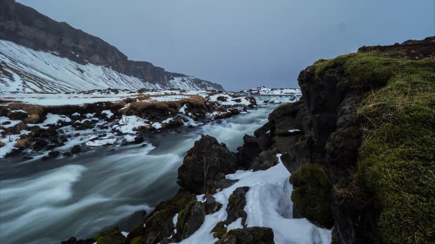 A river flows past rocky snow covered banks