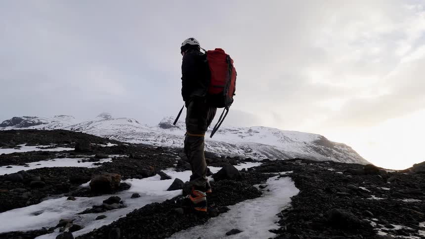 Person wearing a backpack hikes over snowy landscape