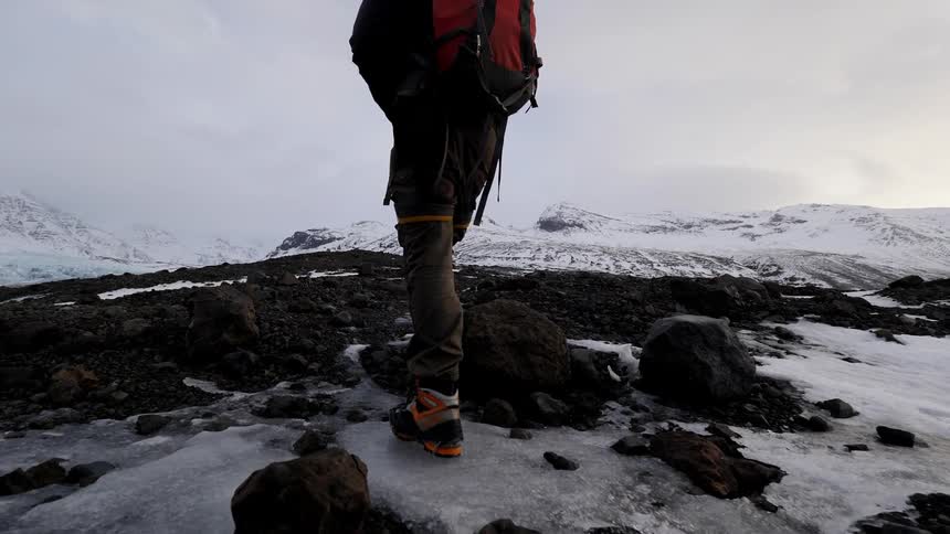 Man wears a backpack as he walks on a mountain