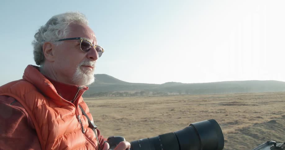 A photographer rides on the outside of a vehicle