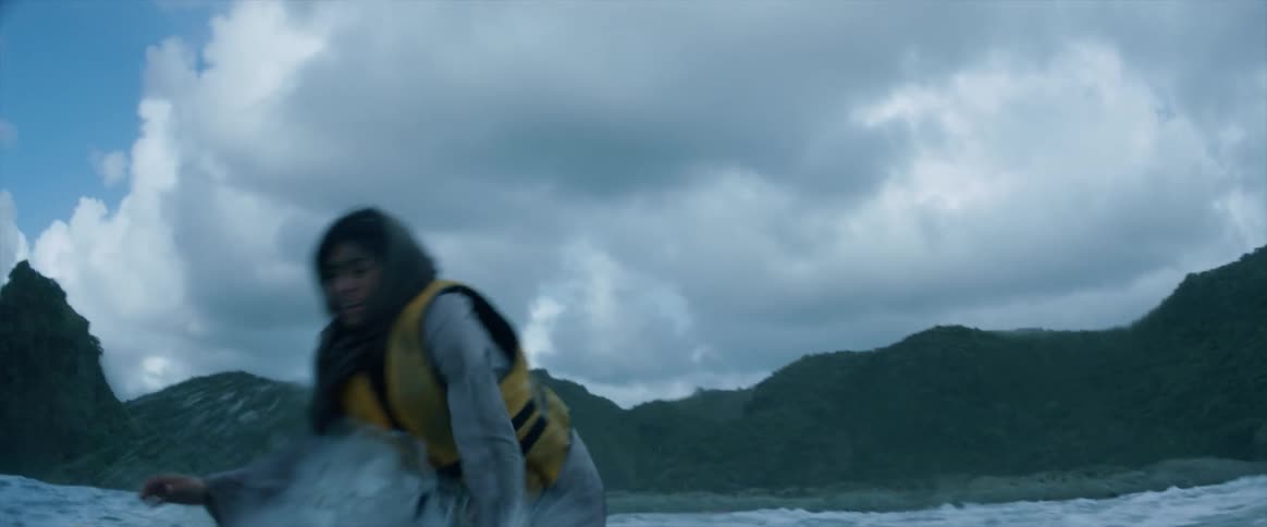 A woman in a life jacket runs through the water