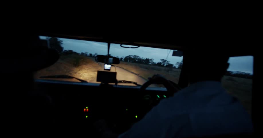 People driving on a dirt road in the early evening