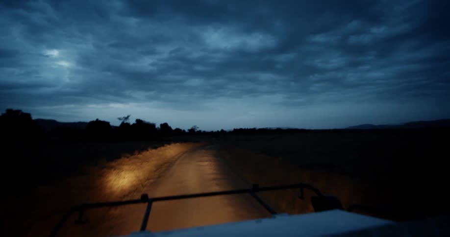 A vehicle drives down a road at night