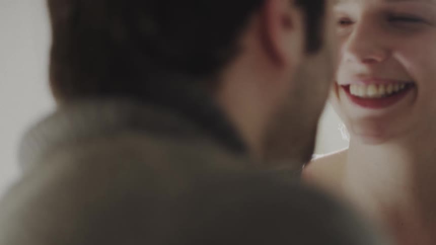 A man and woman smile and kiss