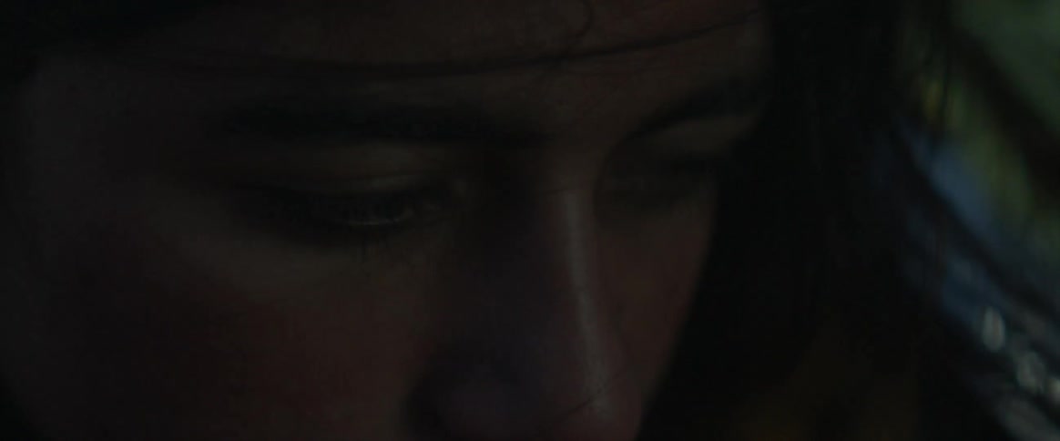 A woman looks forward blinking in the dark